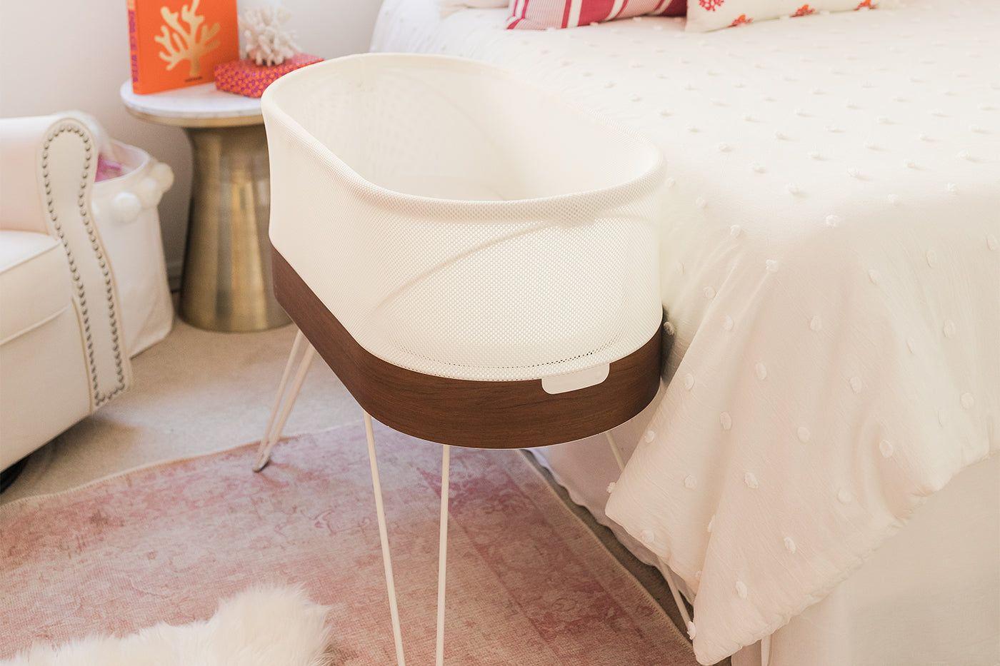 A SNOO Smart Sleeper bassinet next to a caregiver's bed