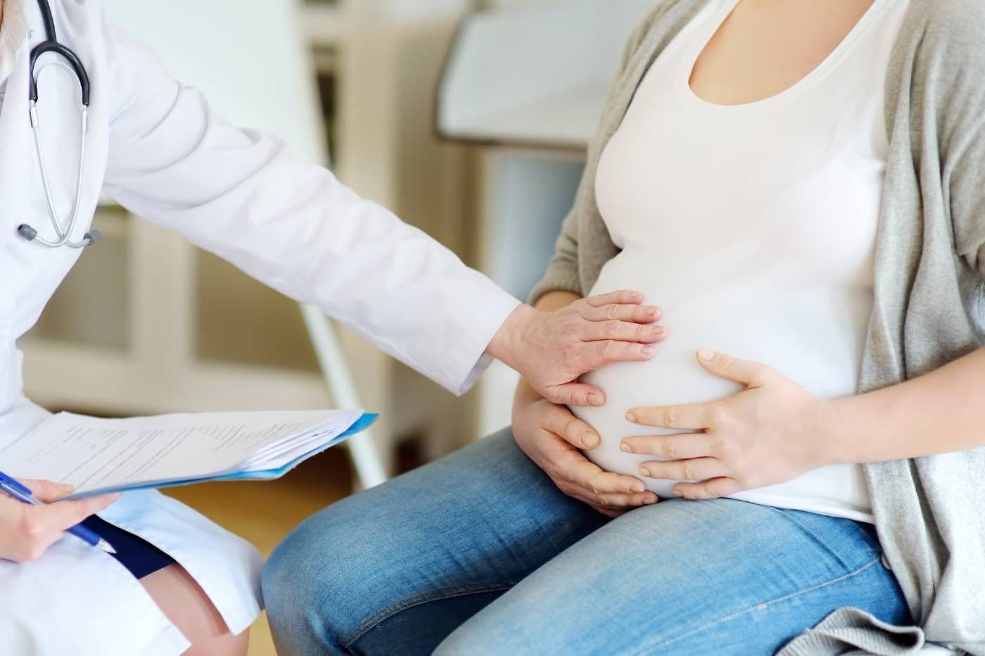 A doctor feels a pregnant person's belly at a checkup.