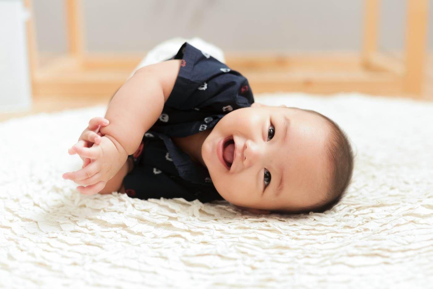 Baby laying on his side and smiling.