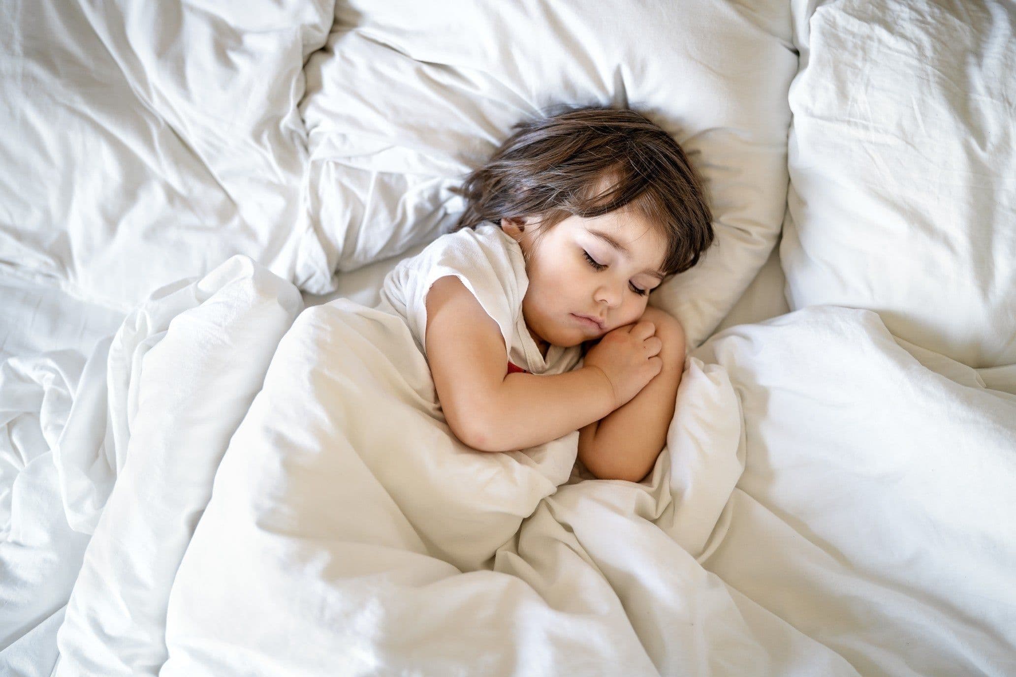 when do kids need a pillow? - toddler sleeping in bed with a pillow