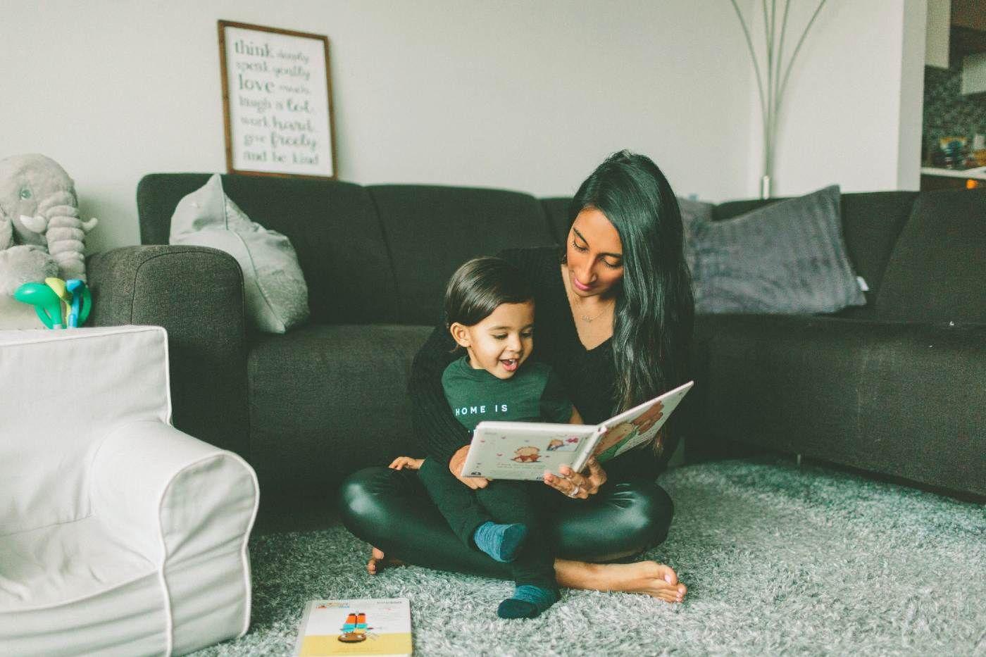 Children's Books in French - mother reading a picture book to toddler son on the carpet