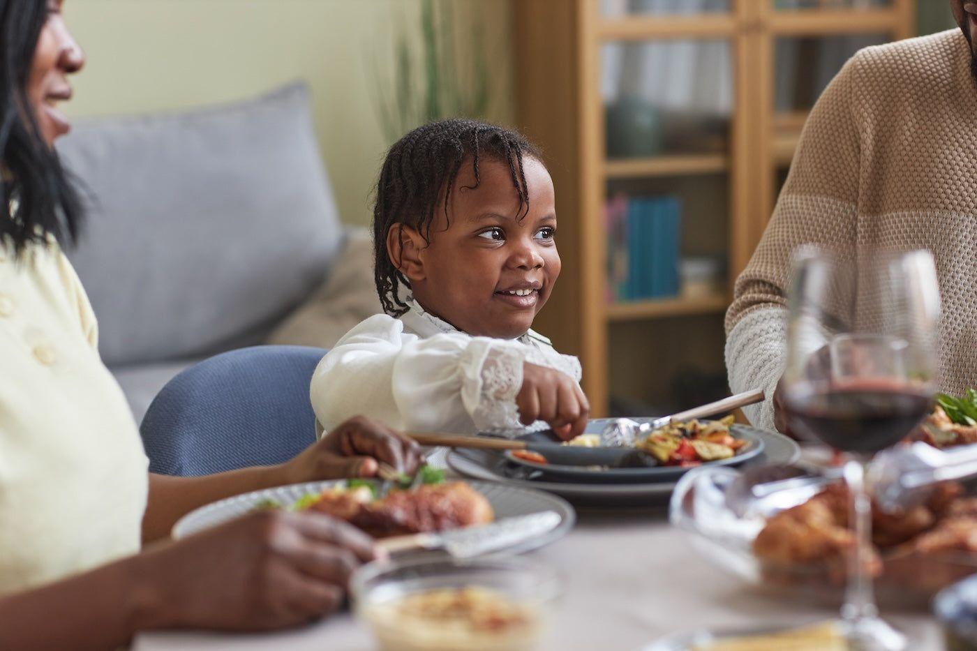 A toddler girl eats at the dinner table
